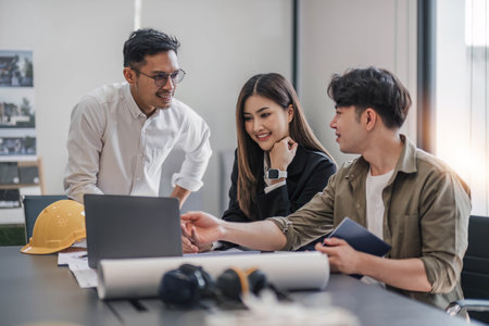 Civil engineer teams meeting working together wear worker helmets hardhat on construction site in modern city. Foreman industry project manager engineer teamwork. Asian industry professional team.の写真素材
