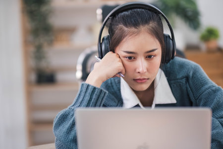 Bored young asian girl student studying, looking upset at laptop screen, attend boring online classes or lecture. Tired bored lazyの写真素材