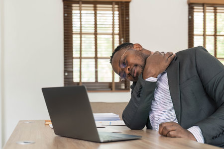 Young african man working at the office using computer laptop suffering pain on hands and fingers, arthritis inflammation.の写真素材