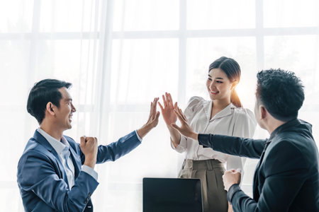 Business Team Achievement Success Mission Concept. Happy successful business team giving a high fives gesture as they laugh and cheer their successの写真素材