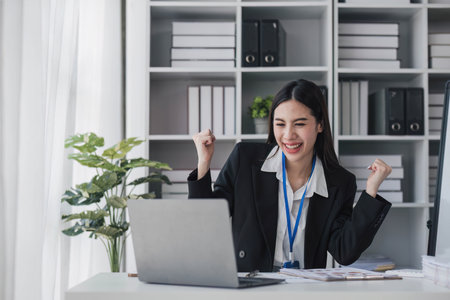 Asian business are excited about celebrating business success with inspiration from their excellent financial results that are happy working in a modern office on a computer..の写真素材