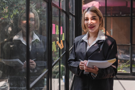 Young businesswoman creative team using post  notes in glass wall to writing strategy business plan...