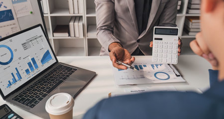 Two business people talk project strategy at office meeting room. Businessman discuss project planning with colleague at modern workplace while having conversation and advice on financial data report.の写真素材