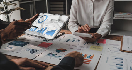 Business People Meeting using laptop computer,calculator,notebook,stock market chart paper for...