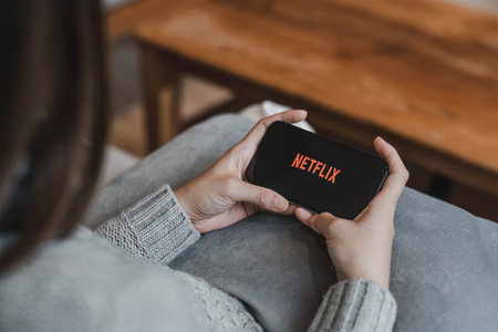 CHIANG MAI, THAILAND, APR 17, 2022: Woman hand holding Smart Phone with Netflix logo on Apple iPhone...