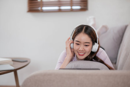 Happy young woman using laptop at home sitting on soft couch. Lady is working on laptop computer. Girl student is typing message using laptop keyboard.の写真素材