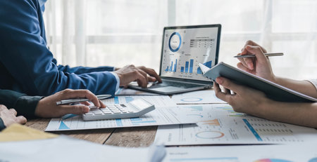 Business People Meeting using laptop computer,calculator,notebook,stock market chart paper for...