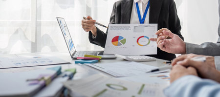Business People Meeting using laptop computer,calculator,notebook,stock market chart paper for...
