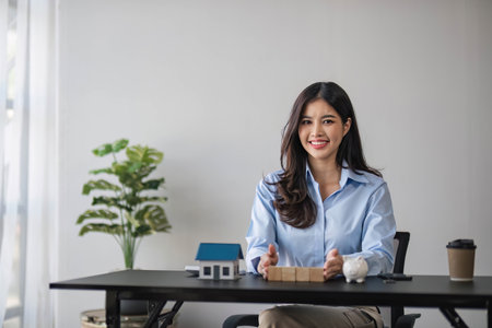 Woman holding white house model and house key in hand.Mortgage loan approval home loan and insurance concept.の写真素材