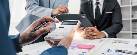 Business People Meeting using laptop computer,calculator,notebook,stock market chart paper for...