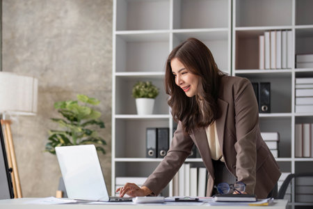 Asian business are excited about celebrating business success with inspiration from their excellent financial results that are happy working in a modern office on a computer.の写真素材