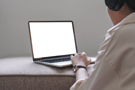 Closeup asian woman using laptop screen web camera while wearing headphones and sitting on the rug...