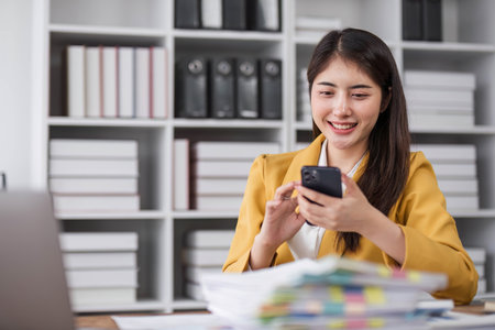 Portrait smile beautiful business asian designer woman with yellow suit working office desk using phone computer. Small business employee freelance online sme marketing e-commerce telemarketing.の写真素材