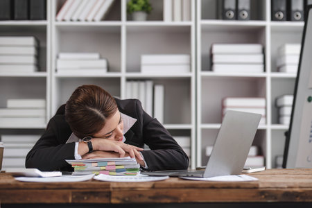 Asian businesswoman who is exhausted from work sleeping on the desk in the office.の写真素材