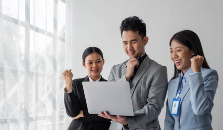 Solving problems as one team. Asian young team of male and female working together while sitting at their working place in office, enjoy, looking at the camera.の写真素材