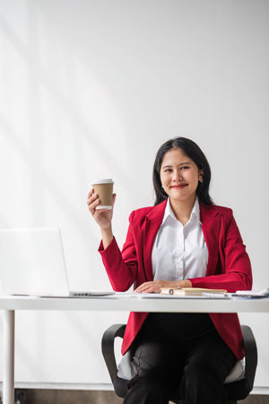 Cheerful business lady working on laptop in office, Asian happy beautiful businesswoman in formal suit work in workplace. Attractive female employee office worker smile.の写真素材