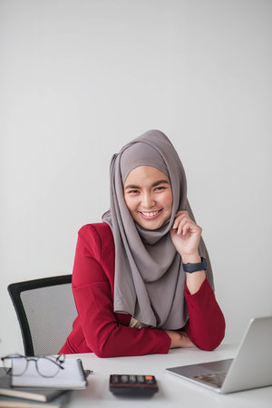 Portrait of beautiful muslim businesswoman smiling at the camera, sitting at her desk.