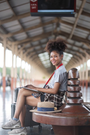 Young woman girl female sitting use computer laptop and travel bag suit case on the floor at station
