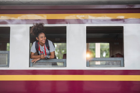 Young asian travel by train sticking her head out of the train, Happy smiling woman female girl looks out from train window travelling by trainの写真素材