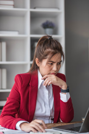 Young Asian businesswoman working on laptop computer, stressed has a headache and thinks hard from work at the office.の写真素材