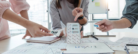 A close-up of an ux ui developer and an ui designer working on a mockup icon interface for a mobile...