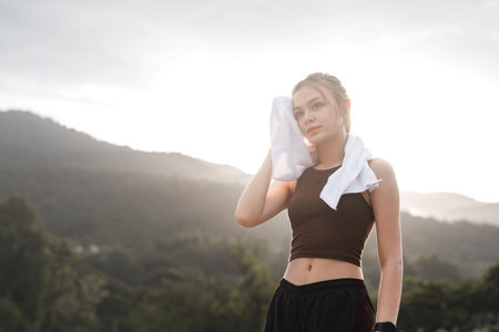 Portrait Young beautiful Asian woman wiping sweat after evening jogging in the park.の写真素材