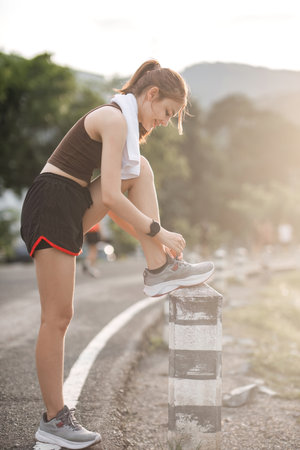 Portrait of a young woman tying her shoes to prepare for exercise.