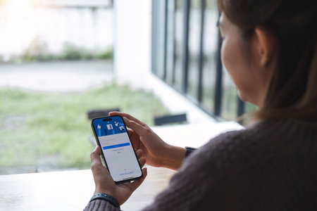 CHIANG MAI, THAILAND - JUL 7, 2023: Facebook social media app logo on log-in, sign-up registration page on mobile app screen on iPhone 14 in persons hand working on e-commerce shopping businessのeditorial素材