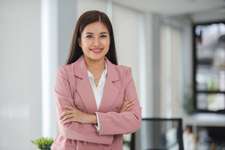 Portrait, Successful businesswoman leader in suit standing in office with arms crossed.の写真素材
