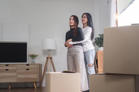 Two young women are carrying cardboard boxes in their room on the day of the move.の写真素材