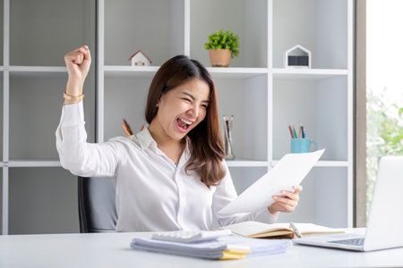 Cheerful and successful businesswoman celebrating with great satisfaction in the company.の写真素材