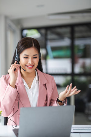 A call center operator is explaining job details to a customer on a laptop.の写真素材