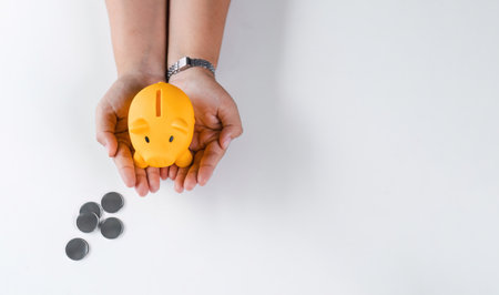 Woman holding piggy bank over coins, savings for future investment concept, top viewの写真素材