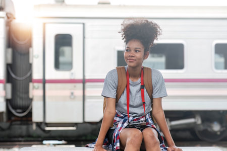 Young Asian African woman traveler with backpack in the railway train station, traveler girl walking...