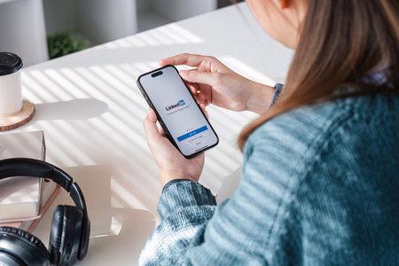 CHIANGMAI, THAILAND - AUG 18,2023 : A women holds Apple iPhone X14 with LinkedIn application on the screen.LinkedIn is a photo-sharing app for smartphones.のeditorial素材