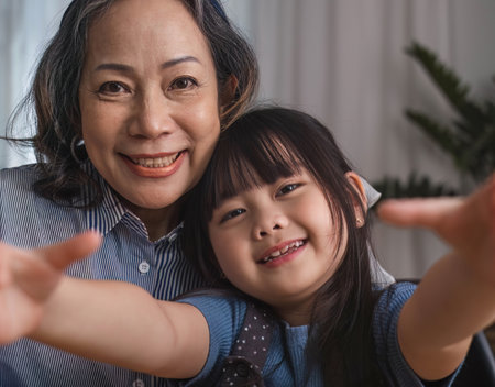 Grandma and granddaughter happily sit and play together in the living room.の写真素材