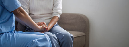 Happy patient is holding caregiver for a hand while spending time together. Elderly woman in nursing...