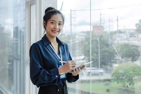 A beautiful and professional Asian businesswoman or female boss using her digital tablet while...