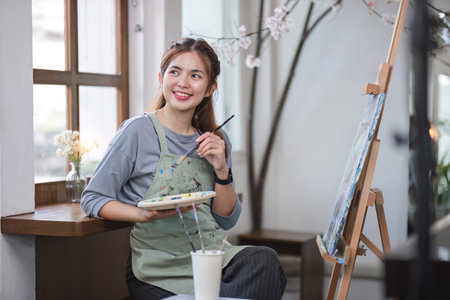 Portrait of a young female artist working on an abstract acrylic canvas painting in an art painting studio.の写真素材