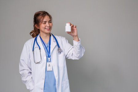 young asian lady doctor in white medical uniform with stethoscope using computer laptop talking video conference call with patient at desk in health clinic or hospital.の写真素材