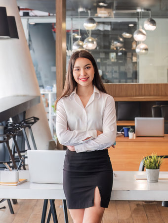 asian businesswoman standing with arms looking at camera in the office.