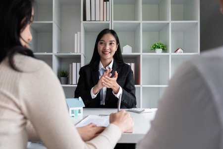 House plans with agents and couple clients Discuss the purchase contract, whether to get insurance or a real estate loan.の写真素材