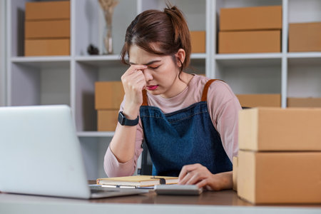 Asian woman think hard serious working laptop computer at home selling online start up small business owner, e-commerce ideas concept.の写真素材