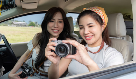 Cute Asian female friends enjoying taking photos with a camera together during a trip. and enjoy traveling on holidaysの写真素材