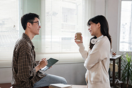 A happy young Asian man and a pretty girl are working on a laptop together, working on a co-project,...