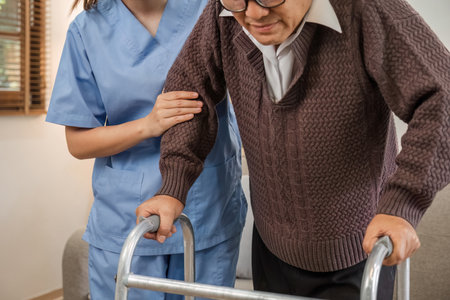 Asian woman caregiver helping senior man walking. Nurse assisting he old man patient at nursing home. Senior man using walker being helped by nurse at home. Elderly patient care and health lifestyleの写真素材