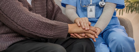 Happy patient is holding caregiver for a hand while spending time together. Elderly man in nursing home and nurseの写真素材