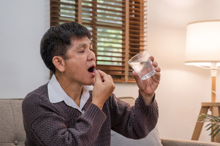 Medicine and hand of Elderly 60s with watery medicine feeling sick Elderly person going to take painkiller from headache, painkiller, health, medicine, treatment, therapy, patient, disease conceptの写真素材
