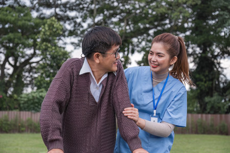 Asian female caregiver helps senior man walk A senior using a walker is assisted by a nurse at home....