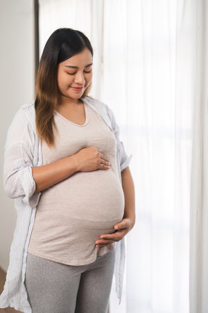 Portrait of a beautiful young woman during the third trimester of pregnancy Pregnant woman with arms on round belly, smiling, relax expression.の写真素材